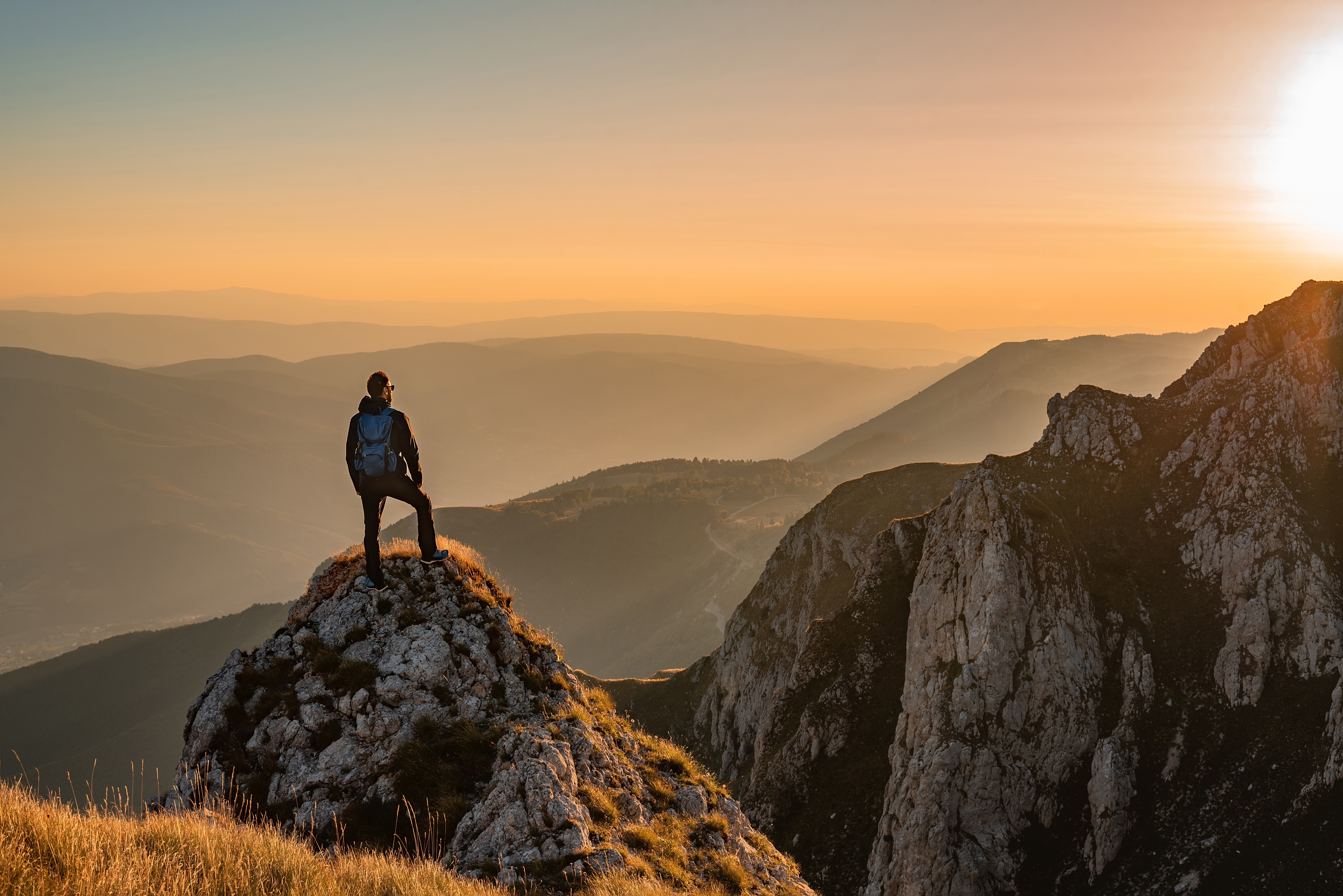 A man at the top of a mountain with a hiking backpack on — If you experience altitude sickness,  IV therapy for altitude sickness with Vida-Flo can help manage symptoms. 